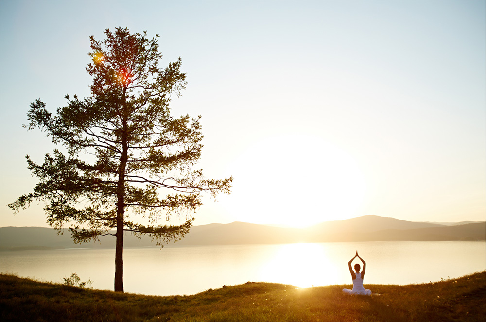 Megan Shahan's Power of Principles - Woman sitting in yoga pose greeting the sunrise.