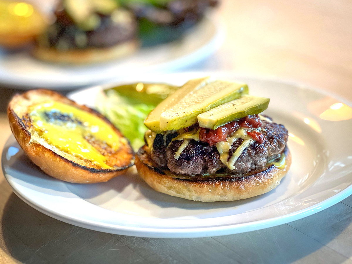 Picture of a LeftCoast GrassFed burger with pickles and cheese on a bun